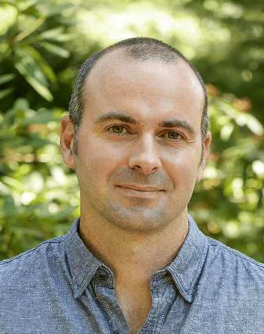 Homme souriant à l'extérieur avec un arrière-plan de verdure