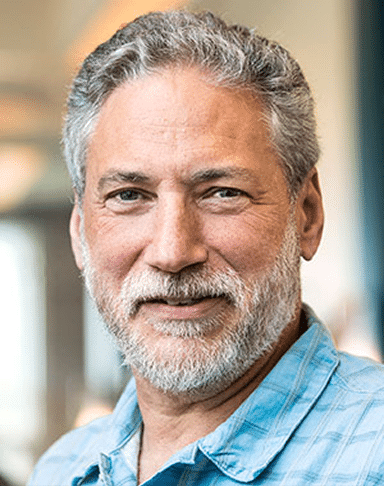 Homem grisalho sorridente com camisa azul, retrato