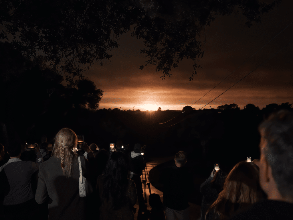 Crowd photographing dramatic sunset under dark clouds
