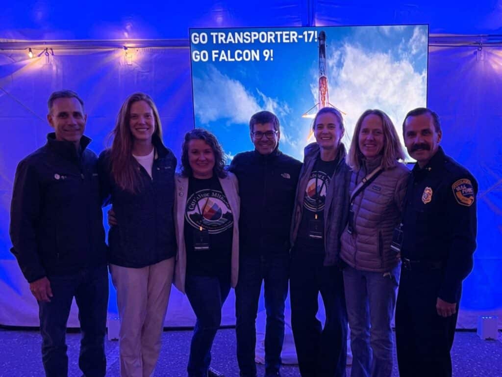 Group posing before Falcon 9 launch screen